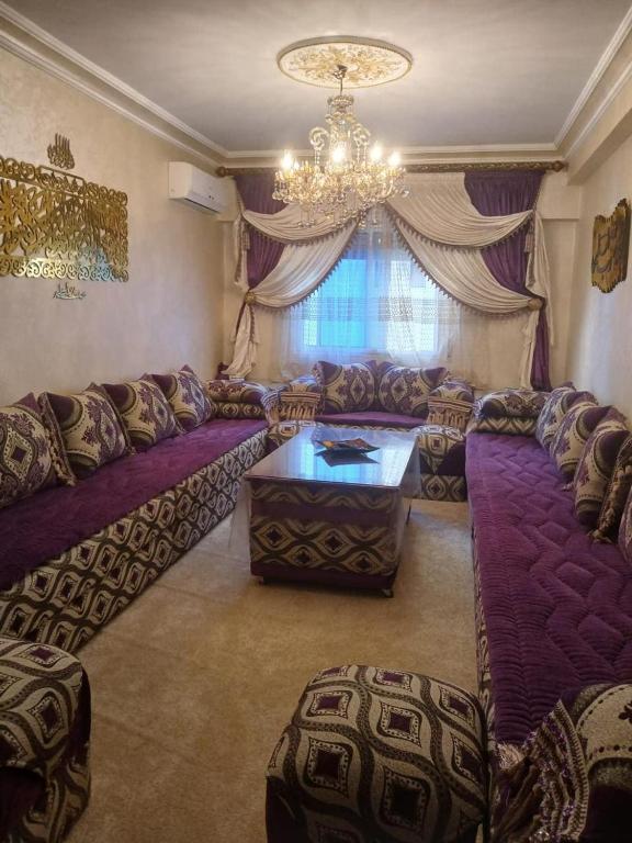 a living room with purple couches and a chandelier at App de luxe sur complexe ATANMIYA de MARTIL in Martil