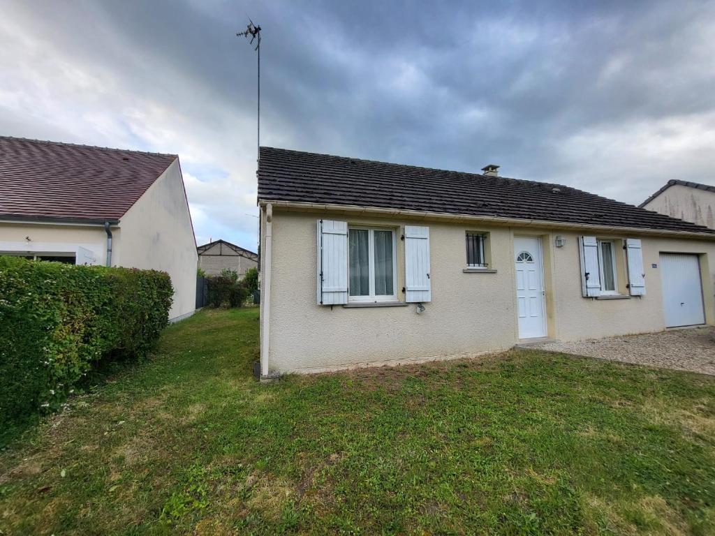 a white house with white windows and a yard at La Parenthèse Immo in Amilly