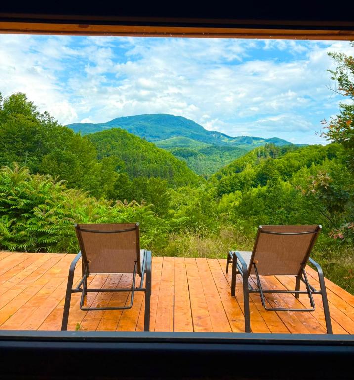 two chairs sitting on a deck with a view of mountains at Firiza Nature Lodges in Baia Mare