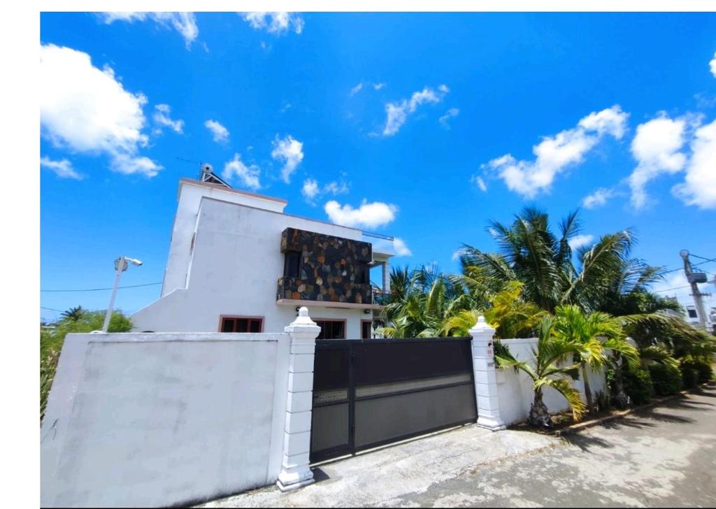 a white house with a fence and palm trees at Georgios Villa in Grand-Baie