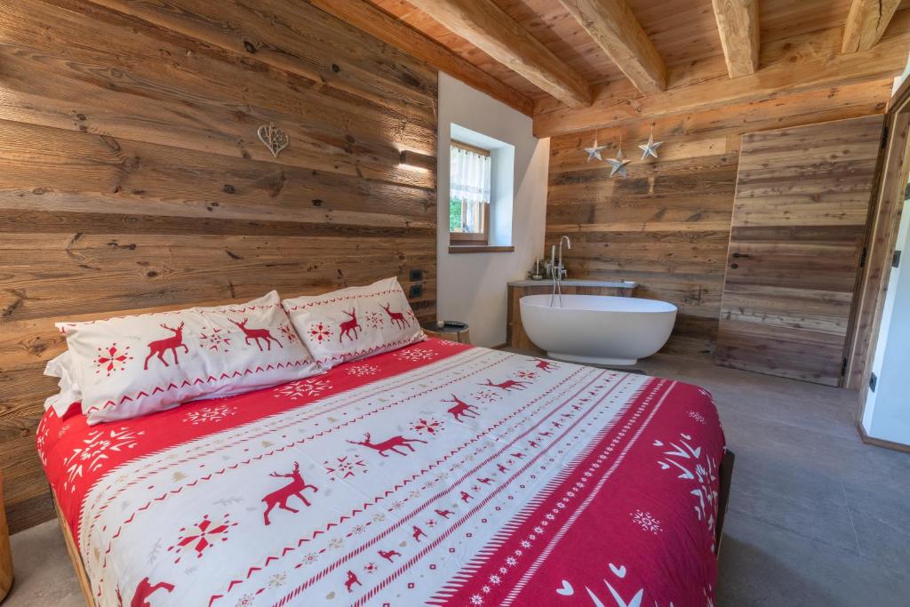 a bedroom with a bed and a tub in a bathroom at Chalet Grifone - Chalet Maso Vecchio nel cuore del Lagorai Trentino in Castello Tesino