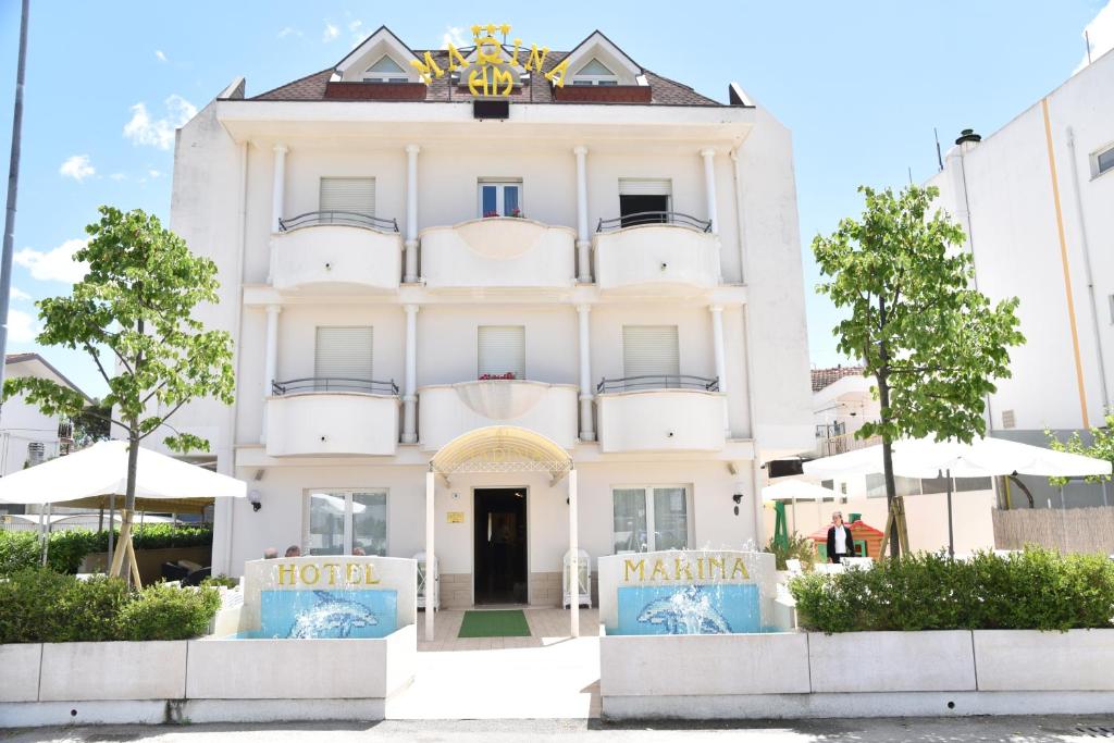 a white building with a sign in front of it at Hotel Marina in Riccione