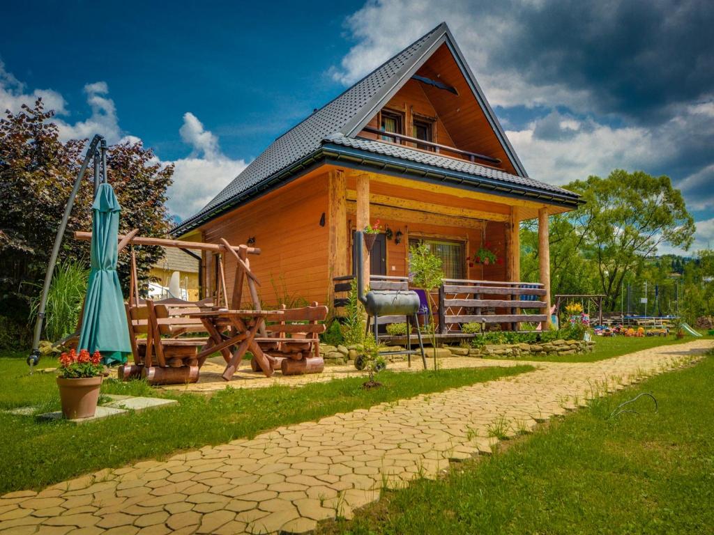 ein kleines Holzhaus mit einer Terrasse und einem Sonnenschirm in der Unterkunft Chaty Anety Domki Całoroczne in Solina