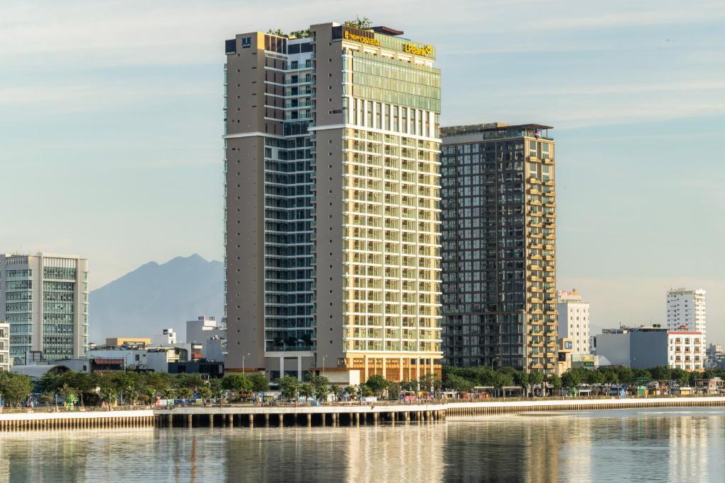 a tall building next to a body of water at TUI BLUE Han River in Danang