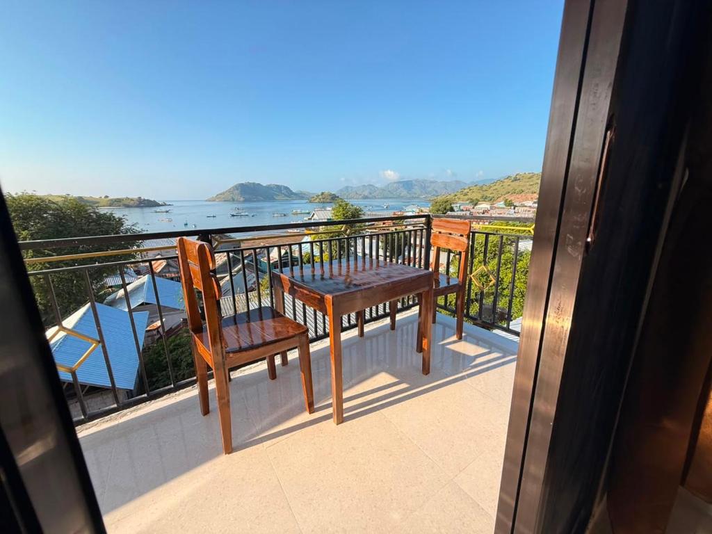 a balcony with two chairs and a table and a view of the water at Zayeed putra komodo in Komodo