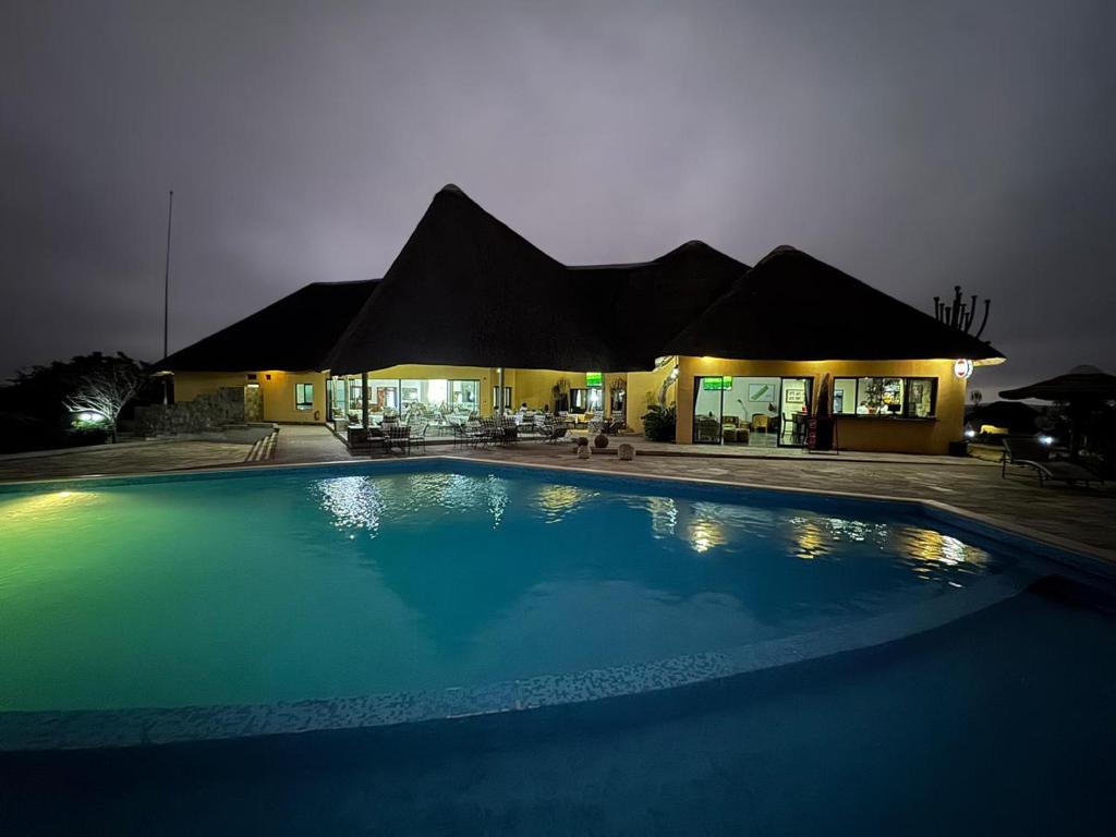 a large swimming pool in front of a house at night at Lodge Kapembawé in Benguela