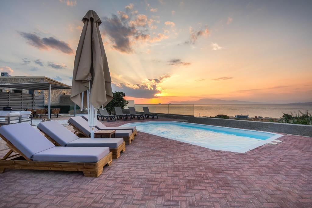 a pool with chaise lounge chairs and an umbrella at Summer & Sun in Vathí