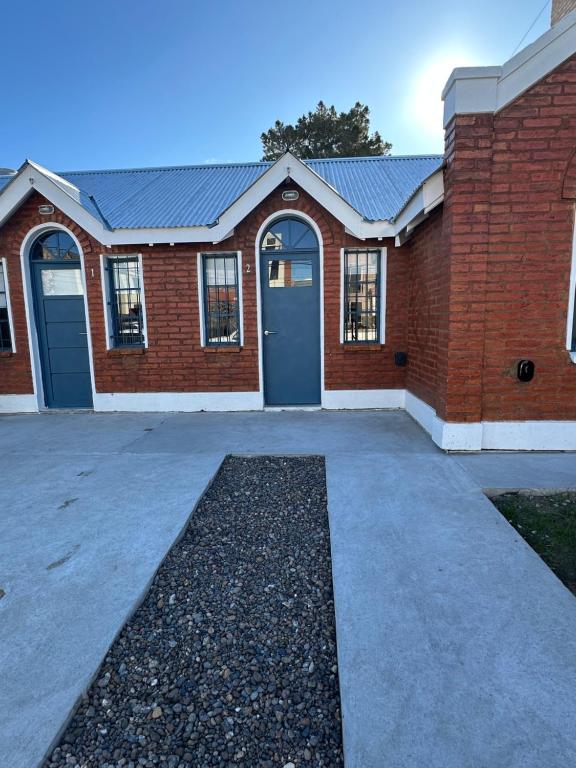a red brick building with a blue door at Solymar Alojamiento in Puerto Madryn