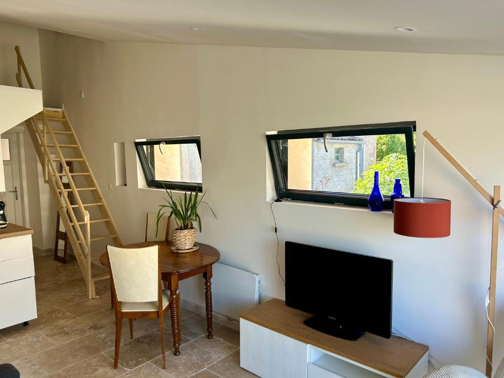 a living room with a television and a table with a chair at Gîte en Provence in Mison