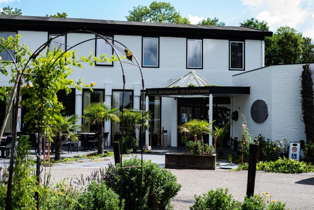 a white building with plants in front of it at Budget Hostel De Elderschans in Aardenburg