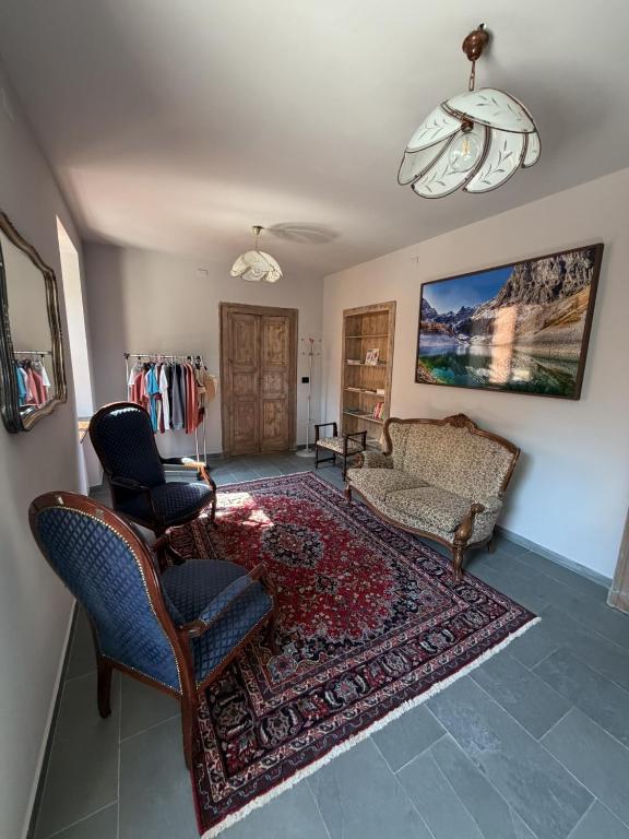 a living room with a couch and chairs and a rug at Rifugio Escursionistico Locanda Borgo Villa in Acceglio