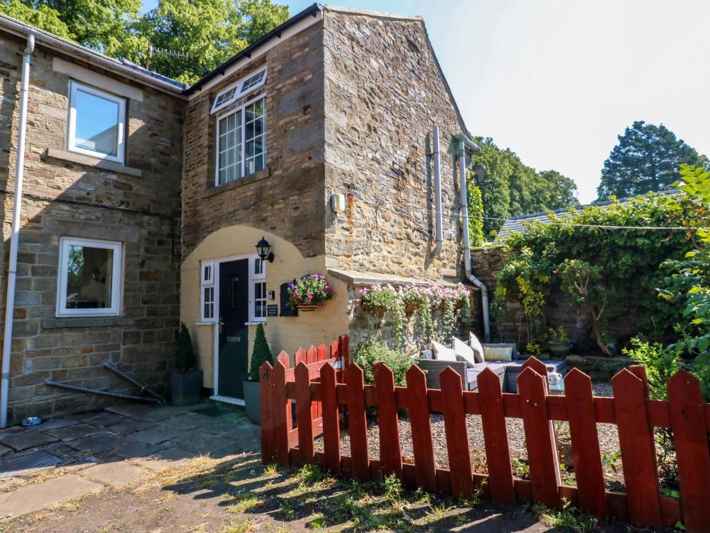 a house with a red fence in front of it at Arch Mews Cottage in Barnard Castle