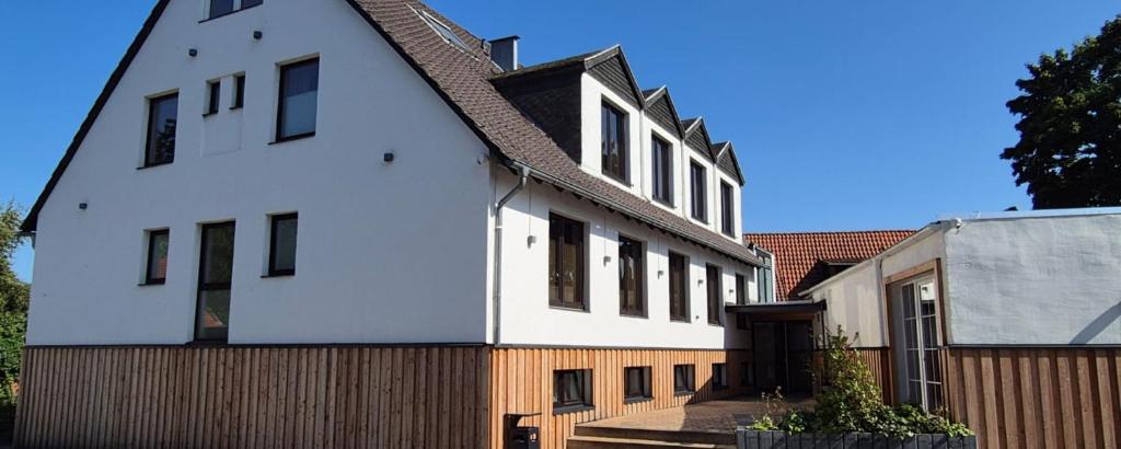 a white house with a wooden fence next to it at Hotel Zollhaus Hülperode in Hülperode