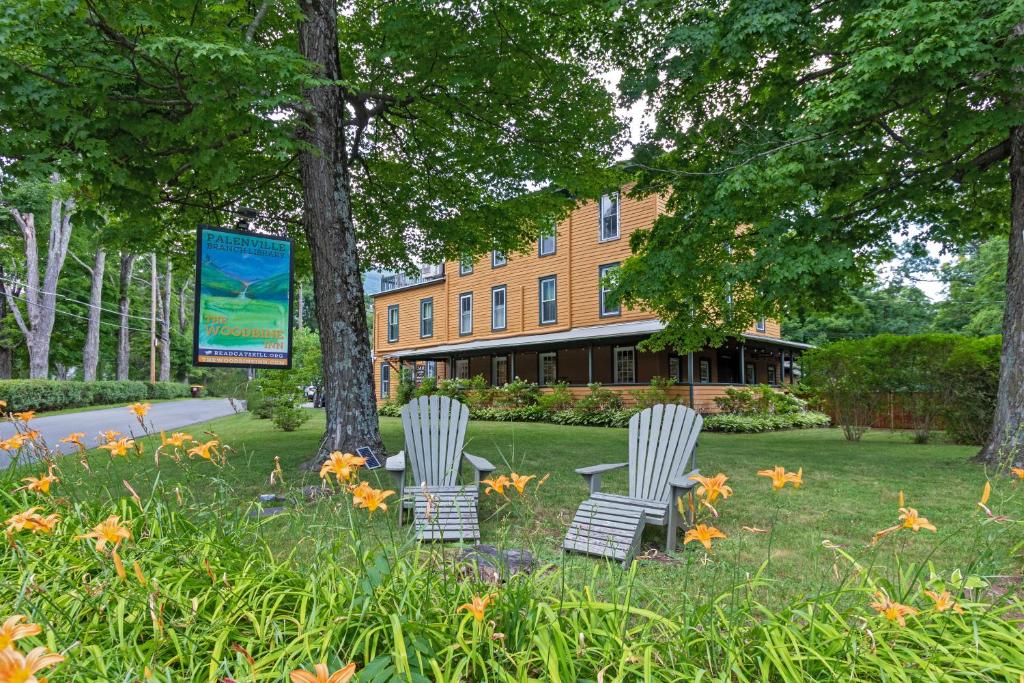 two chairs sitting in the grass in front of a building at The Woodbine Inn in Palenville