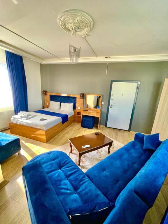 a living room with a blue couch and a bed at Riwaner Hotel in Avcılar