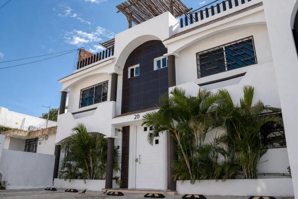 ein weißes Haus mit Palmen davor in der Unterkunft Coco Suites by Andiani Travel in Cancún