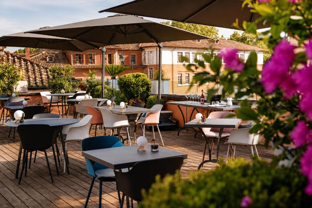 eine Außenterrasse mit Tischen, Stühlen und Sonnenschirmen in der Unterkunft DOM Hotel Roma - Preferred Hotels & Resorts in Rom