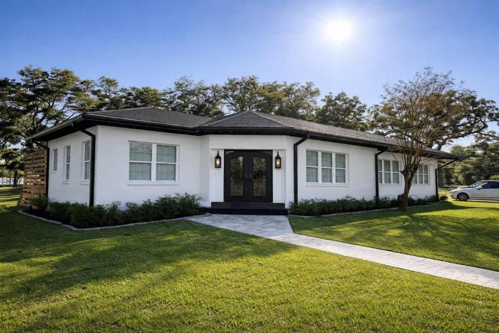 a white house with a grass yard at Steps from beach with open fire pit in Gulfport