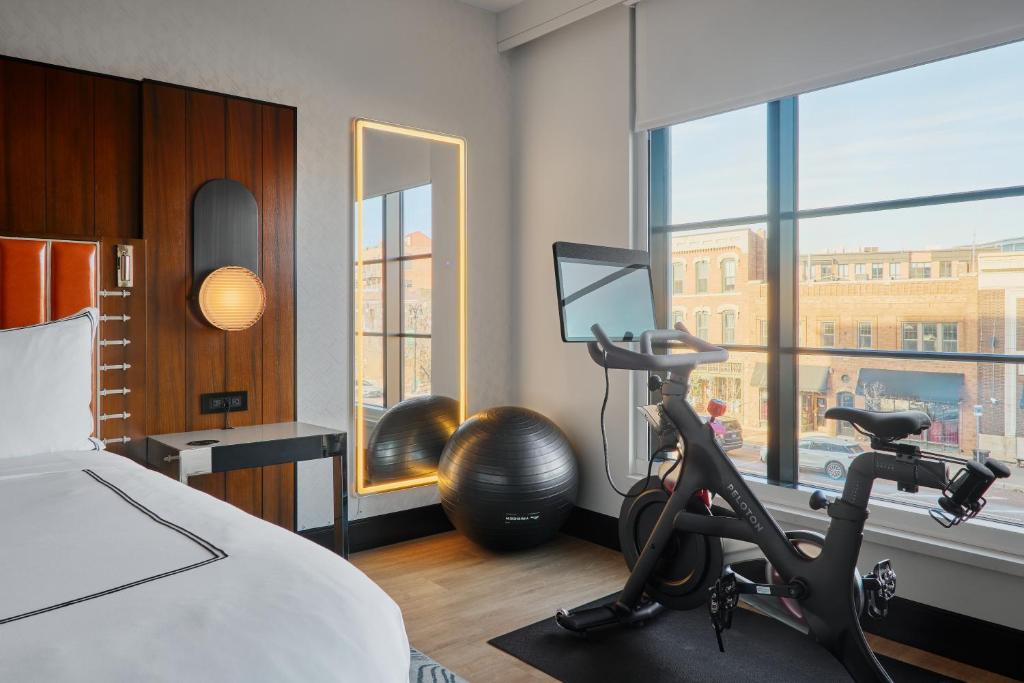 a bedroom with a bed and a gym with a treadmill at The Godfrey Detroit, Curio Collection By Hilton in Detroit