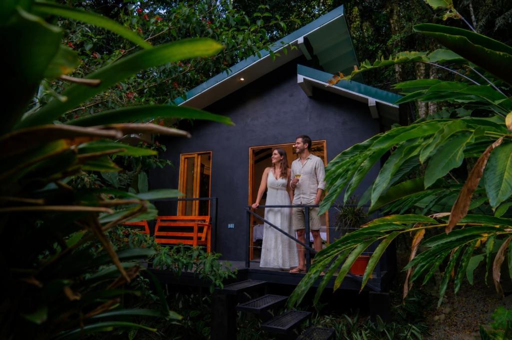 a bride and groom standing on the porch of a house at Jardines Secretos in Rivas