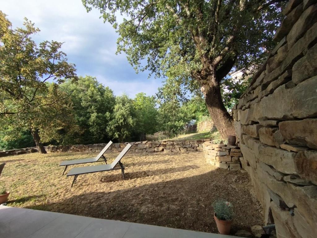 two benches in a park next to a stone wall at Apartma Pod Hrastom in Koper