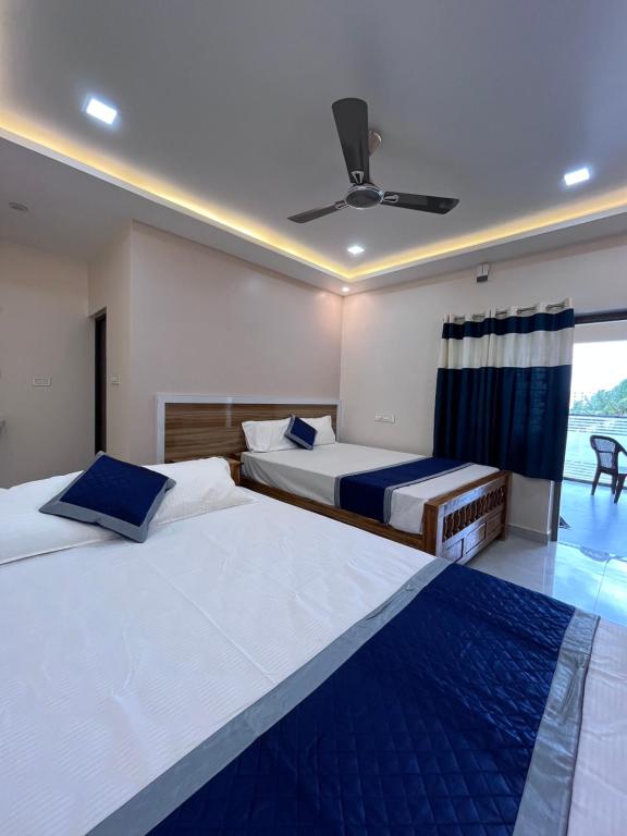 a bedroom with two beds and a ceiling fan at VV Guest House & Rooms in Tiruvannāmalai