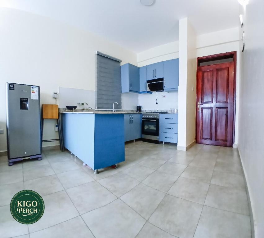 a large kitchen with blue cabinets and a red door at Kigo Perch in Kampala
