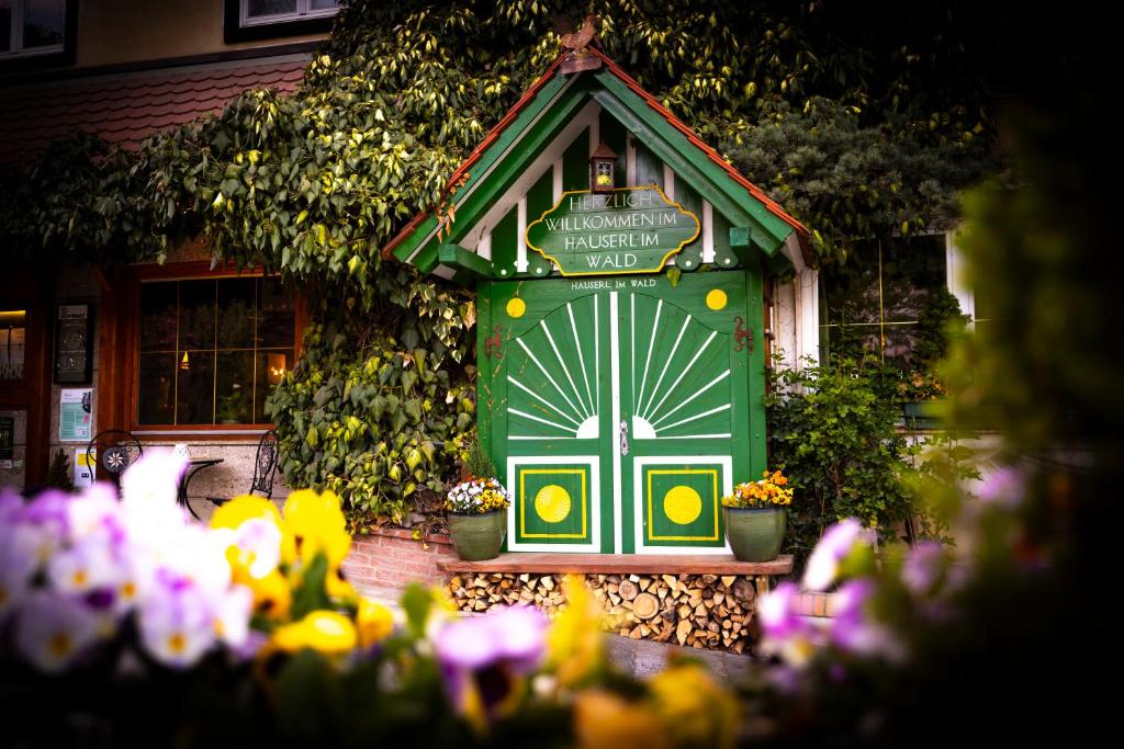 a green door with flowers in front of a house at Hotel Restaurant - Häuserl im Wald Graz in Graz