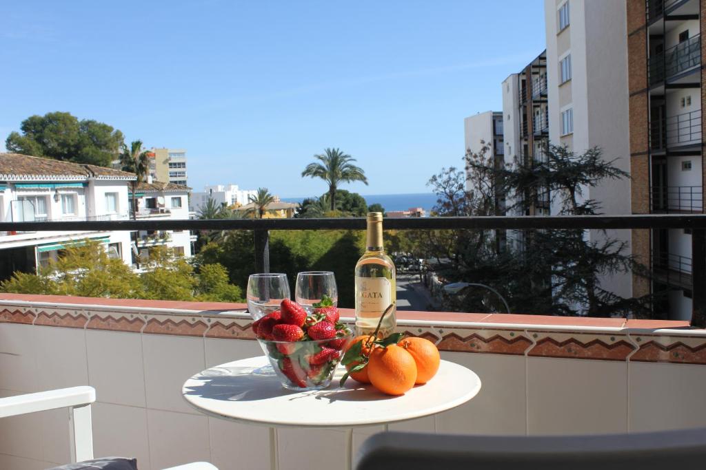 - une table avec une bouteille de vin et des fruits sur un balcon dans l'établissement Bonanza Apartment, à Benalmádena