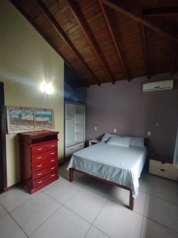 a bedroom with a bed and a dresser at O melhor de Garopaba in Garopaba