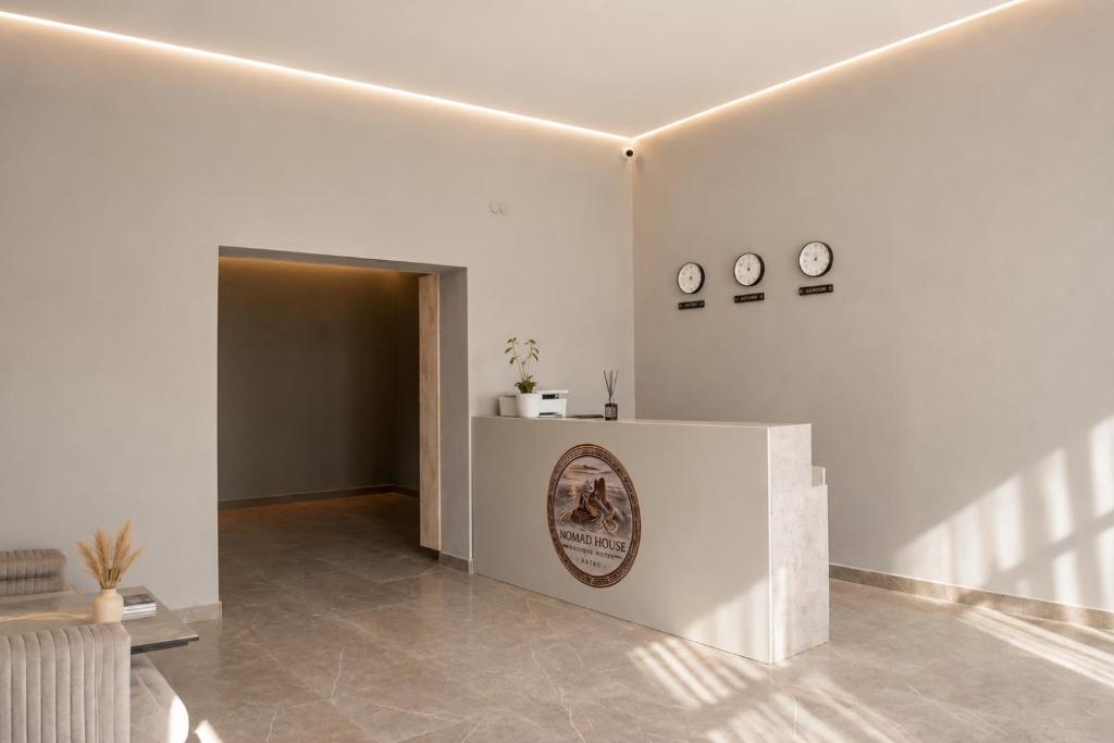 a living room with white walls and a sign on the wall at Nomad Aktau Hostel in Aktau