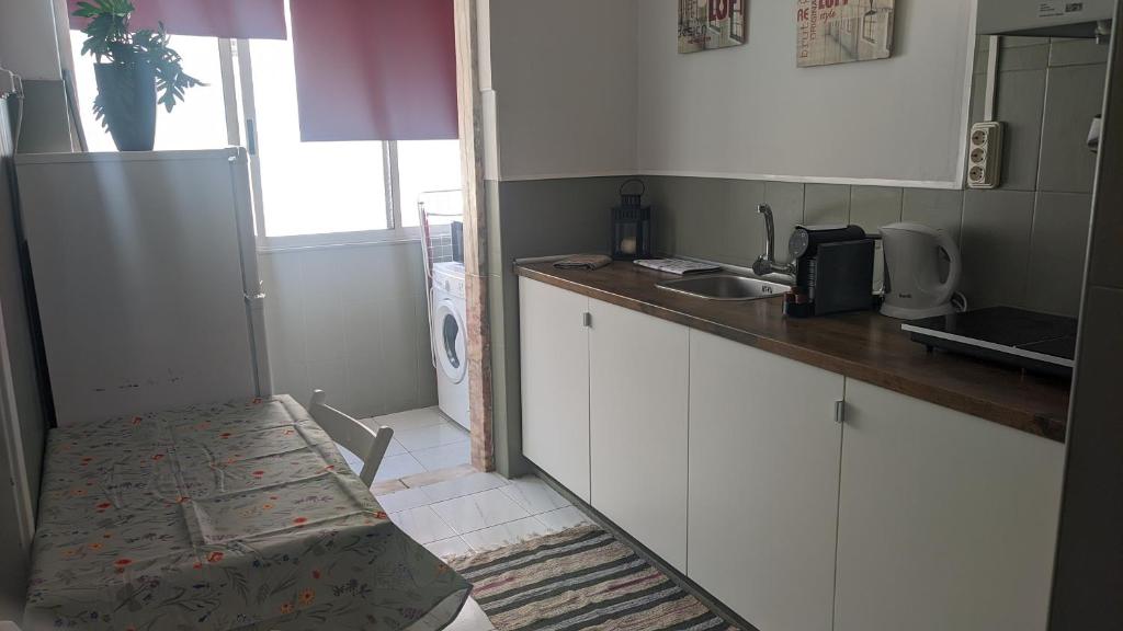 a kitchen with white cabinets and a sink and a refrigerator at Vasco Santana Guesthouse in Odivelas