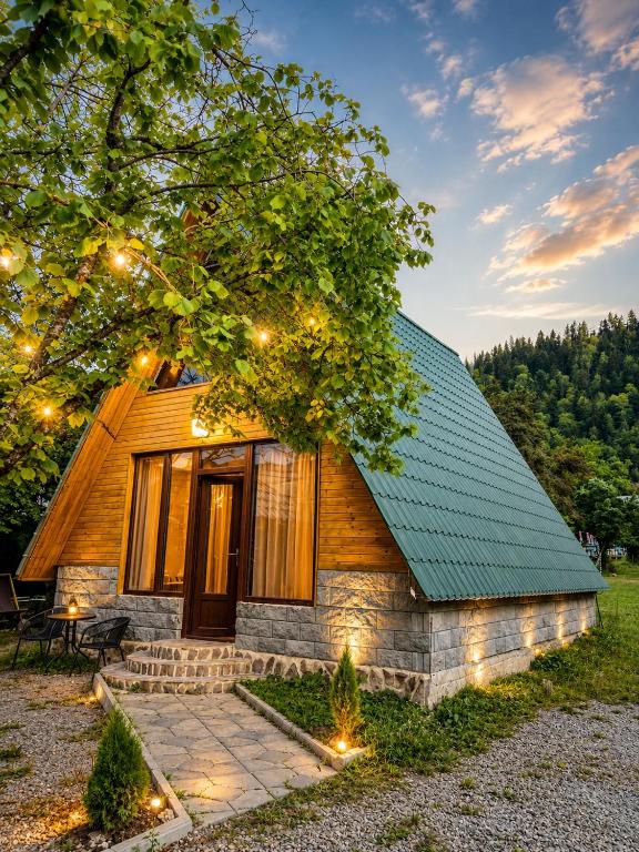 a log cabin with a green roof and lights at Borjomi Twins in Sadgeri
