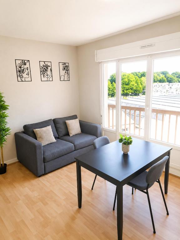 a living room with a couch and a table at L'Élégant - 2 Voyageurs in Reims