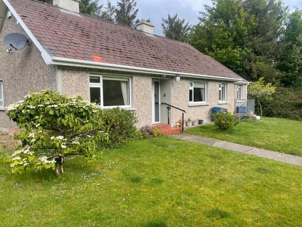 a house with a green yard with a bush at James Neills Cottage in Letterkenny