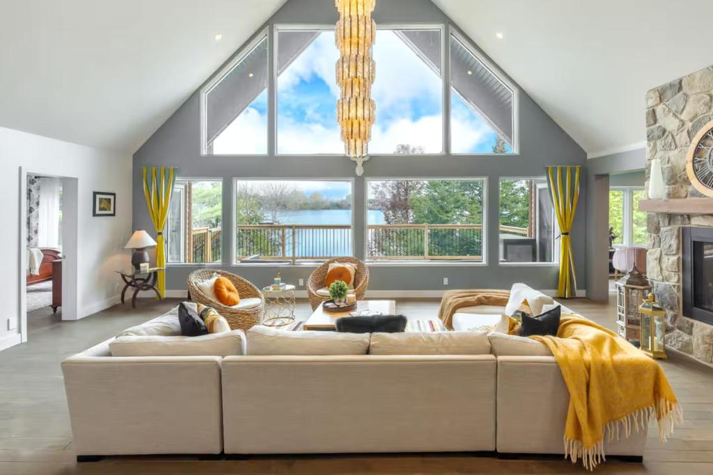 a living room with a white couch and a large window at 5-Br Villa on Lake Labelle Chalet Jacob in Labelle