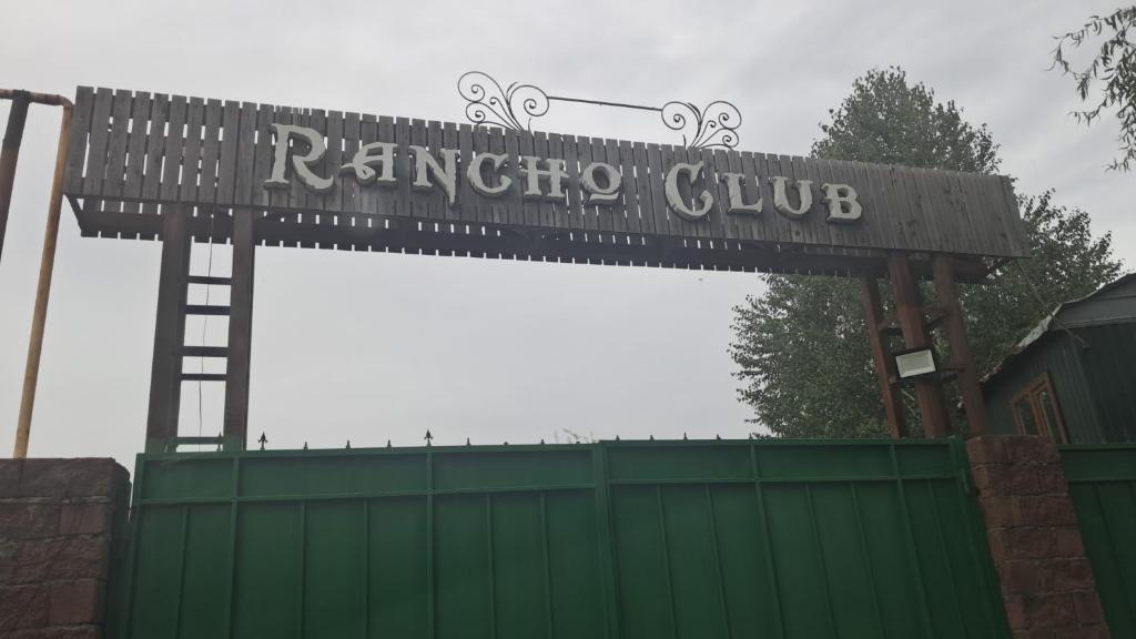 a sign for a ringer club over a green fence at Rancho Otel Almaty in Qaskeleng