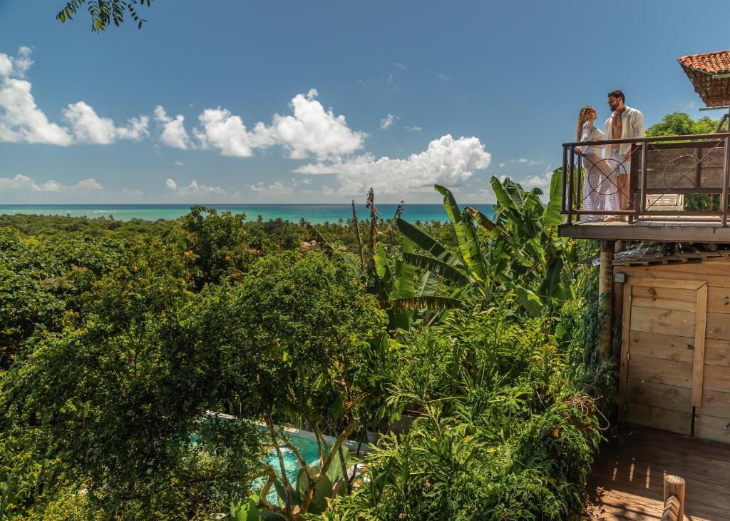 two people standing on a balcony looking out at the ocean at Casa La Torre Hotel Boutique in Trancoso