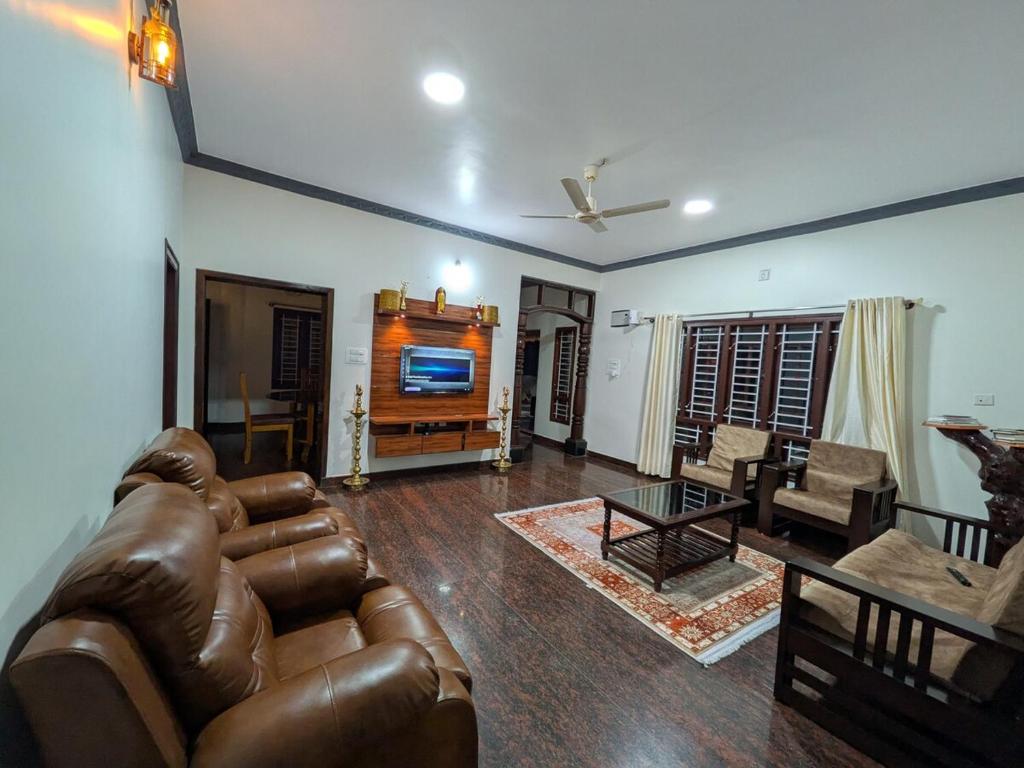 a living room with a leather couch and a television at Cherry guest House Shringeri ,koppa rural in Chikmagalur