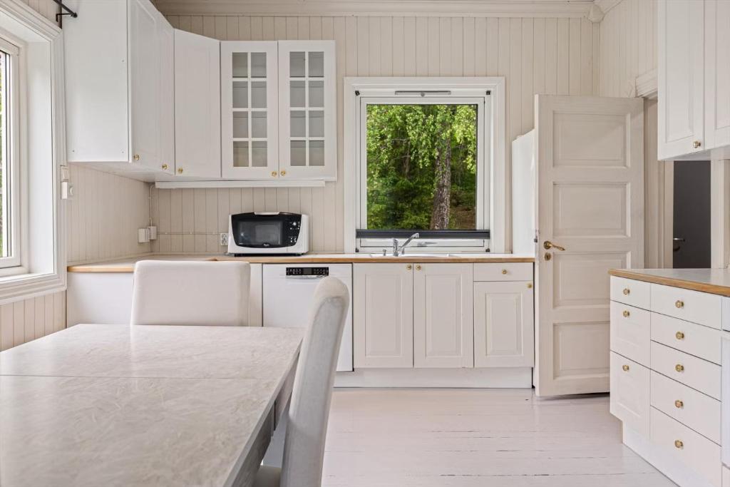 a kitchen with white cabinets and a table and a window at Lobrothaugen in Fagernes