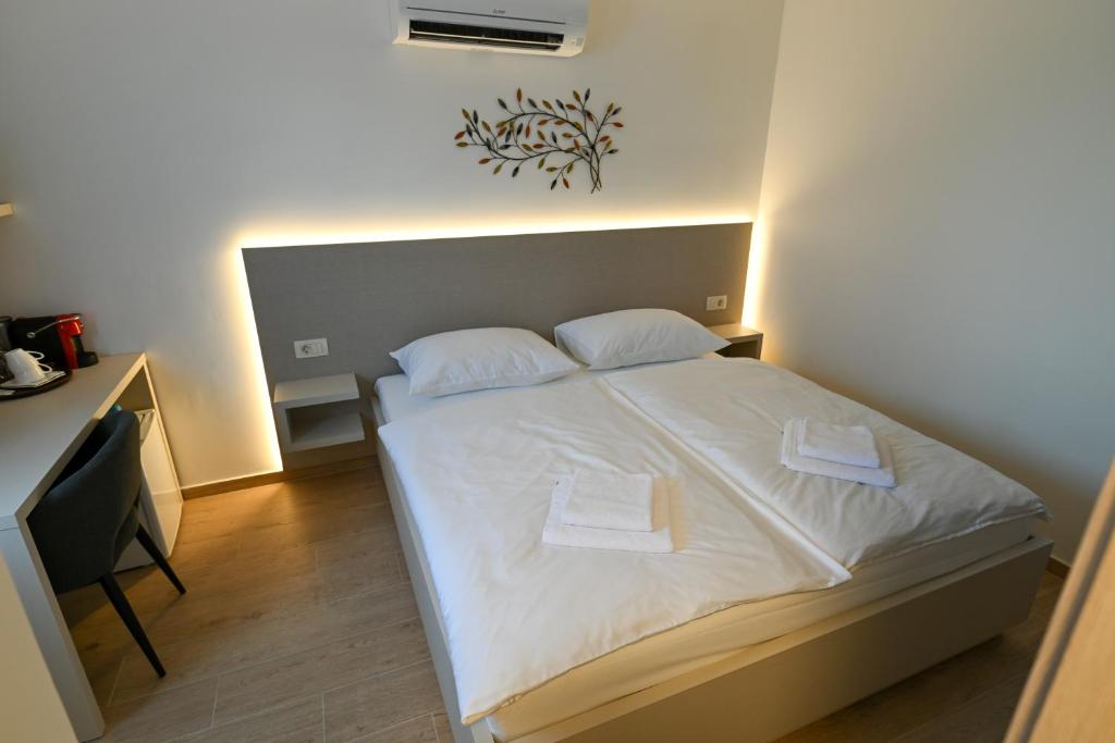 a bedroom with a white bed with two pillows at Terra rossa rooms in Čepljani