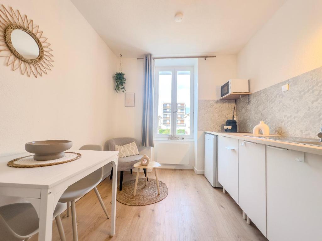 a kitchen with white cabinets and a table with a mirror at Le Charles - Gare - CEA - STMicro in Fontaine