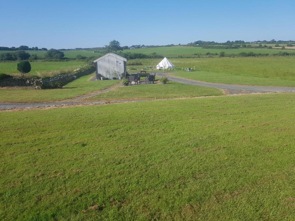 an open field with a white barn in the distance at Sleep4GlampingTent-NearTralee-Countryside in Tralee