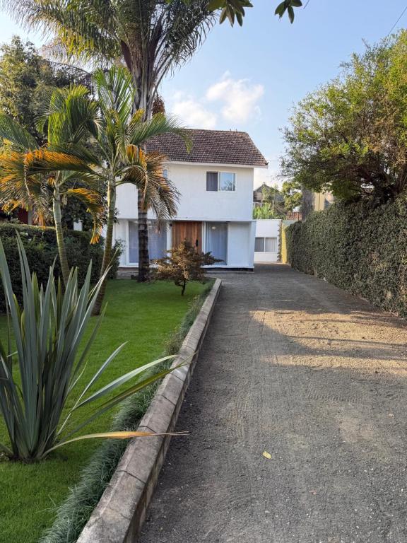 a driveway leading to a white house with palm trees at City Retreat Arusha in Arusha