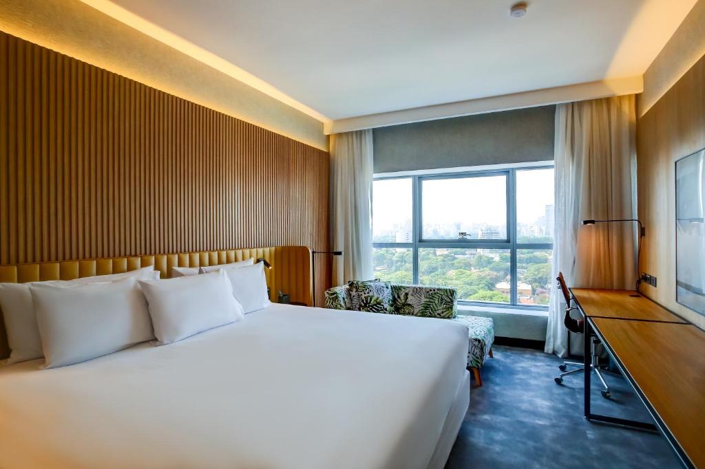 a bedroom with a bed and a desk and a window at Grand Mercure SP Pinheiros in São Paulo