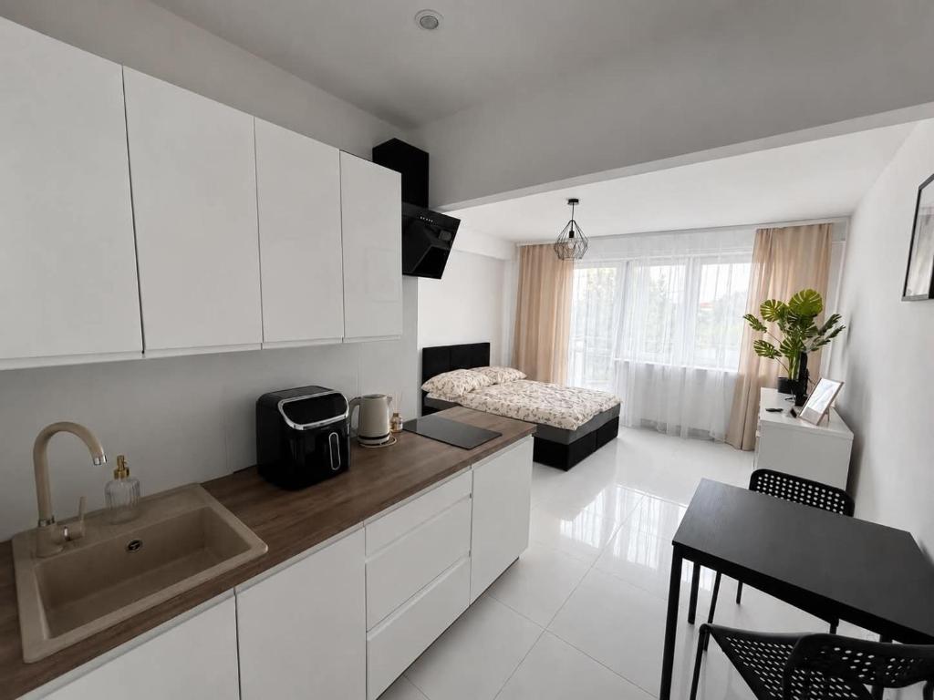a kitchen with white cabinets and a bed in a room at Apartament Mostowa in Brodnica