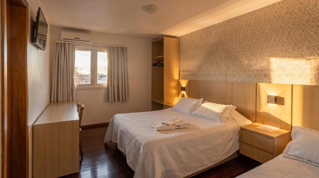 a hotel room with two beds and a window at Hotel Somensi in Bento Gonçalves