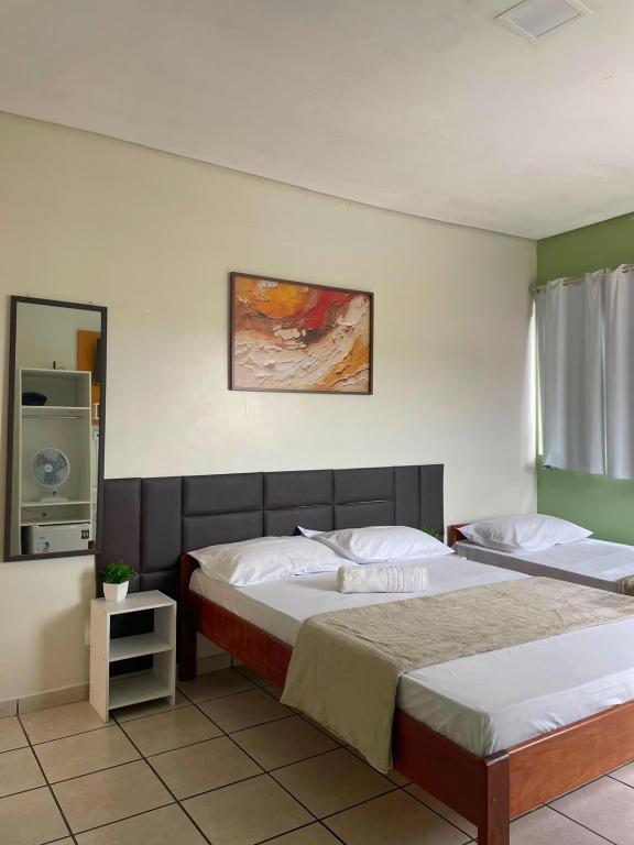 a bedroom with two beds and a painting on the wall at Alameda Hotel Centro in Garanhuns