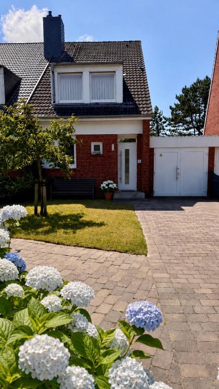 a brick house with white flowers in front of it at Haus SandRast in Westerland