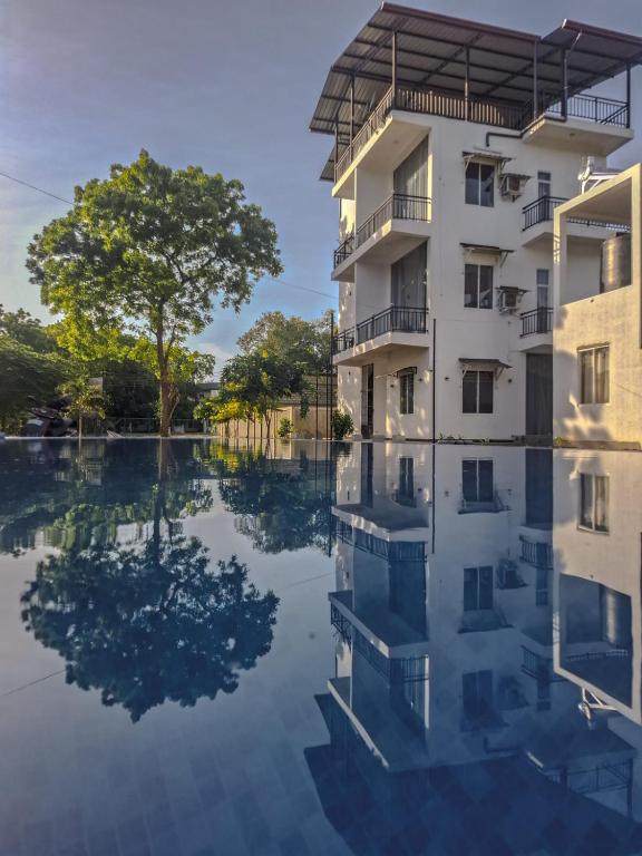 an apartment building with a reflection in the water at Shalom Resorts Yala in Tissamaharama
